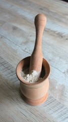 Zeolite in a wooden mortar with a pestle. Zeolite mesolite raw powder on wooden background