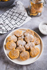 Homemade pumpkin shaped cookies in powdered sugar on a plate on a table vertical view