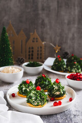 Tuna, egg and dill salad shaped like Christmas trees on crackers on a plate vertical view