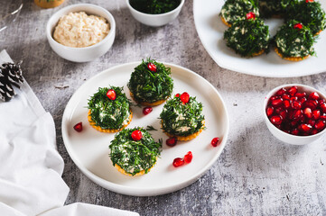 Fish salad in dill on crackers in the shape of Christmas trees on a plate on the table
