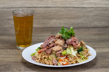 Beef Chow fun rice noodles piled high on the plate combined with an ice cold pint of beer, for a hearty Vietnamese Cuisine meal of chow mein.