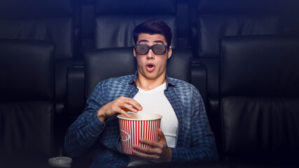 Alone in the movies. Young guy with shocked look on his face in film theater