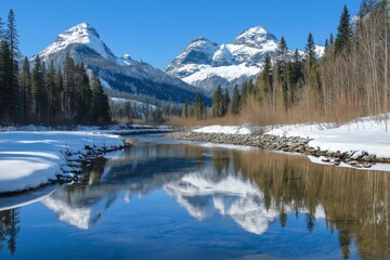 Calm river reflecting snowy mountains and a bright blue sky on a sunny winter day