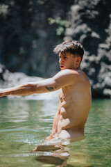 Fototapeta premium Fit man swimming and relaxing in a natural river surrounded by rocky cliffs on a sunny day.