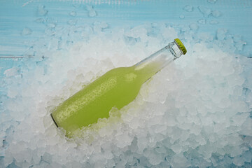 One glass bottle of green drink on crushed ice