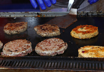 Cook preparing burgers and veggie burgers on hot grill