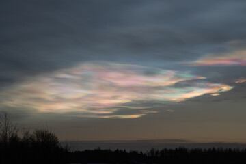 A beautiful display of colorful clouds at sunset over a tranquil landscape in autumn