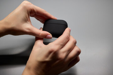 Hands Gently Holding a Stylish and Modern Wireless Earbuds Charging Case for Easy Use