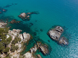 Aerial top down of rocks in blue water Mediterannean Sea along Costa Brava Palamos Catalonia Spain