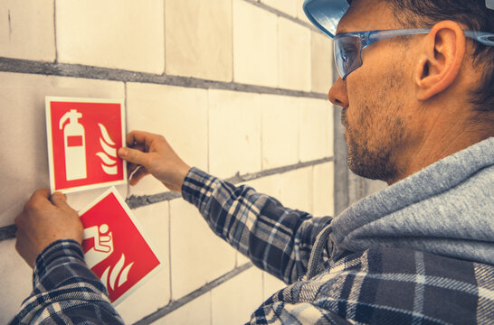 Worker Installing Fire Safety Signs on a Construction Site During Daylight Hours