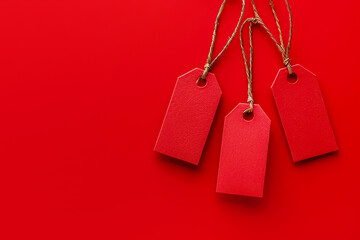 Red sale tags on string against a solid red background for promotional sales display. Copy space