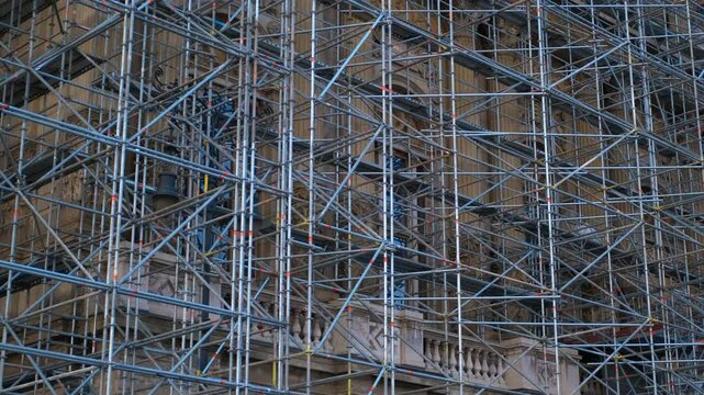 Scaffolding surrounding historic building during restoration project. Workers installing scaffolding on a historic building facade, preparing for extensive restoration work in an urban environment