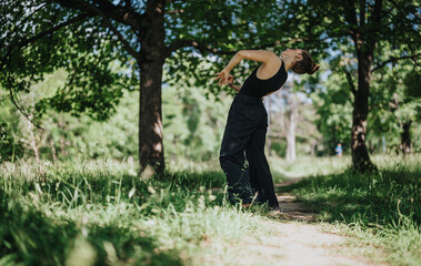 A woman elegantly performs modern dance in a serene natural setting, surrounded by lush green trees and vibrant nature.