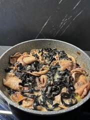 Black Squid Ink Pasta with Seafood in a Pan on a Dark Marble Background