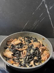 Black Squid Ink Pasta with Seafood in a Pan on a Dark Marble Background