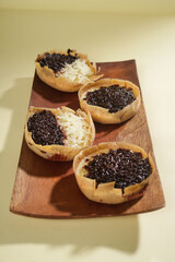 Martabak mini or terang bulan mini is Indonesian popular street food, made from flour, egg, yeast, topped with cheese or chocolate. Mini sweet martabak isolated on yellow background.