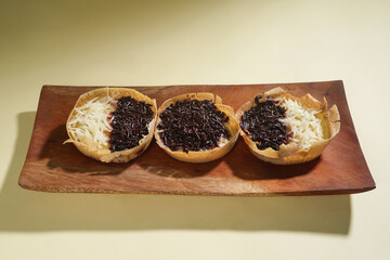 Martabak mini or terang bulan mini is Indonesian popular street food, made from flour, egg, yeast, topped with cheese or chocolate. Mini sweet martabak isolated on yellow background.