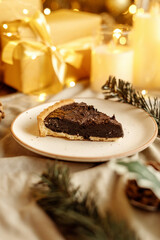 Delicious chocolate tart with Christmas decorations, surrounded by festive ornaments and holiday lights. Perfect dessert for Christmas, holiday gatherings, and winter celebrations.