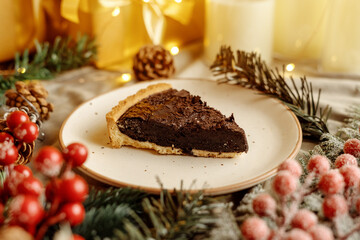 Delicious chocolate tart with Christmas decorations, surrounded by festive ornaments and holiday lights. Perfect dessert for Christmas, holiday gatherings, and winter celebrations.