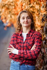 Portrait of a Confident Woman in a Red Checkered Shirt Against an Autumn Background