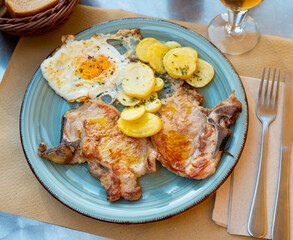Appetizing pork chop served on platter with potatoes and eggs..