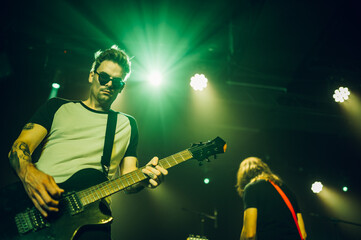 Guitarist performing live on stage under green lights