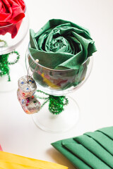 Green paper napkin folded in the shape of a rose, inside a glass..Christmas concept
