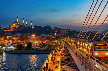 view of the cable-stayed metro bridge with a pedestrian path and the night cityscape of Istanbul, Turkey, the Golden Horn Bay and the architecture of the city