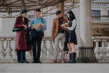 A group of four young people engaging in a business discussion outdoors in a city environment, exuding teamwork and collaboration. The urban background enhances the modern and dynamic atmosphere.