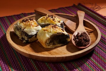Banana bolen is made from banana and pastry skin and has chocolate and cheese filling. Served in wooden plate. Selective focus image.