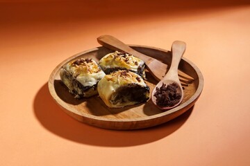 Banana bolen is made from banana and pastry skin and has chocolate and cheese filling. Served in wooden plate. Selective focus image.