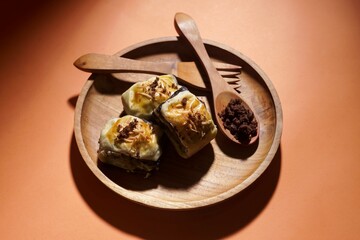 Banana bolen is made from banana and pastry skin and has chocolate and cheese filling. Served in wooden plate. Selective focus image.