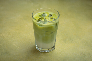 Refreshing iced matcha latte, combining the earthy notes of matcha with the creamy texture of milk, served in a clear glass on a green surface