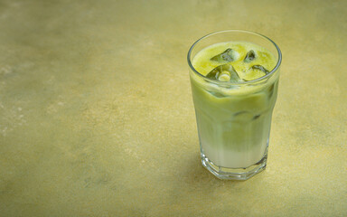 Refreshing iced matcha latte, combining the earthy notes of matcha with the creamy texture of milk, served in a clear glass on a green surface