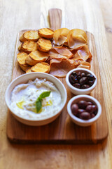 Grilled bread, prosciutto, ricotta spread, and olives on a cutting board