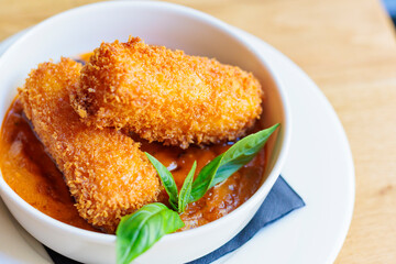 Crispy fried golden croquettes served with sauce on a white plate