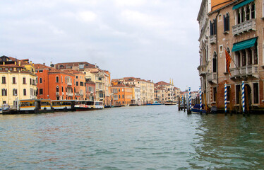 A view of historic Venetian buildings along the Grand Canal, showcasing classic Italian architecture. The iconic canal waters reflect the facades, with boats and gondolas adding to the charm of Venice
