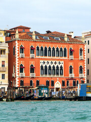 Fototapeta premium A view of historic Venetian buildings along the Grand Canal, showcasing classic Italian architecture. The iconic canal waters reflect the facades, with boats and gondolas adding to the charm of Venice