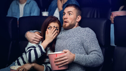 Movie date. Terrified young couple watching scary film in cinema