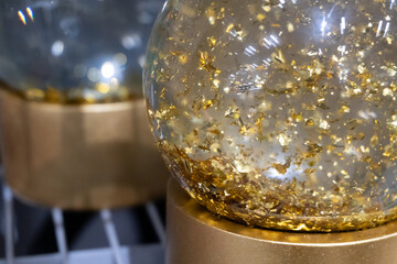A snow globe with gold foil inside. The transparent sphere, filled with shimmering particles, embodies harmony and celebration.