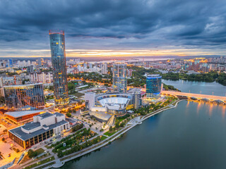 Fototapeta premium Yekaterinburg city and pond aerial panoramic view at summer or early autumn sunset. Night city in the early autumn or summer.