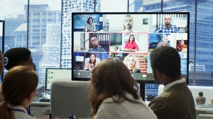 Company employees attending a meeting via videocall with investors, discussing about the future of the enterprise. Advisory board and workers examining infographics data for management. Camera A.