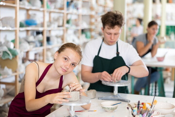 Students teenage girl and teenage boy sculpt ceramic product from raw clay in workshop