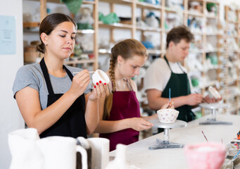 Pottery master together with his students applies a pattern to pottery in the workshop