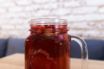 Close-up of a transparent cup with rich red raspberry tea with ginger. The deep color of the drink radiates warmth, while the subtle hints of ginger add a spicy touch.