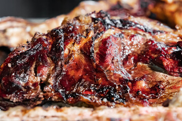 Close-up of juicy grilled meat on barbecue, rich, caramelized texture with charred edges