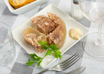Traditional russian dish kholodets served on table with chrain and parsley sprig.