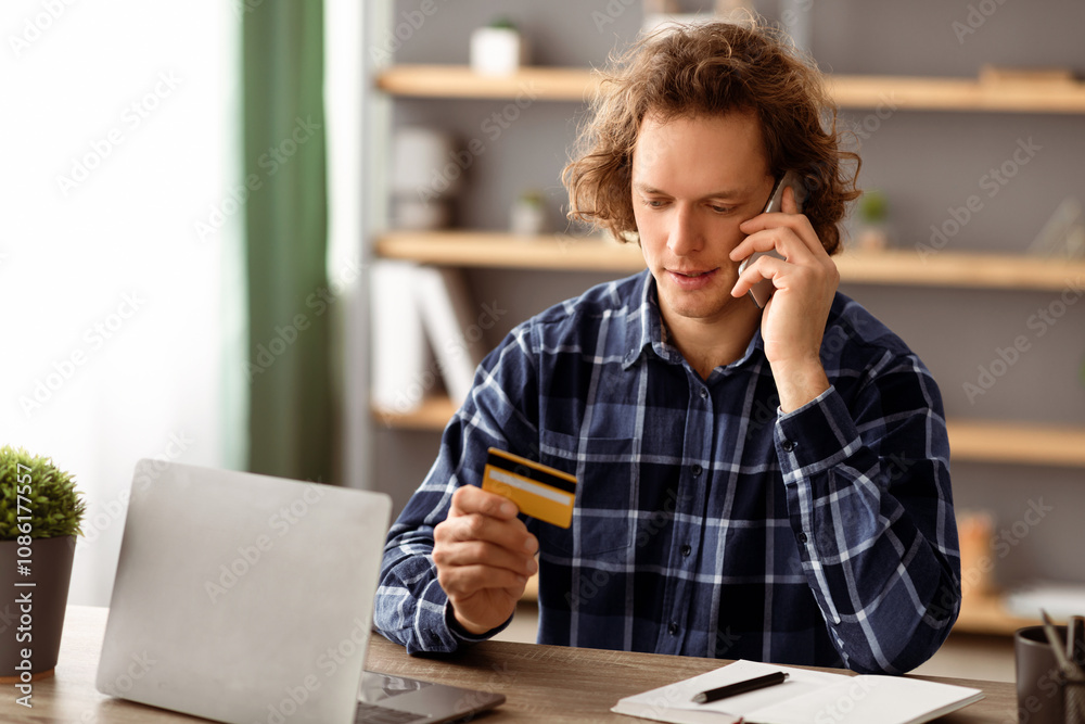 Poster man calling to bank holding credit card having problem with payment shopping online sitting at lapto