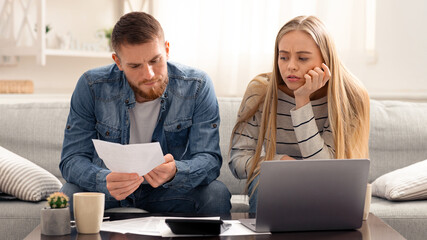 Annual tax report. Unhappy couple reading bank notification, calculating budget at home