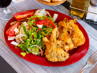 Appetizing chicken legs with seafood and summer salad of tomato and bell pepper